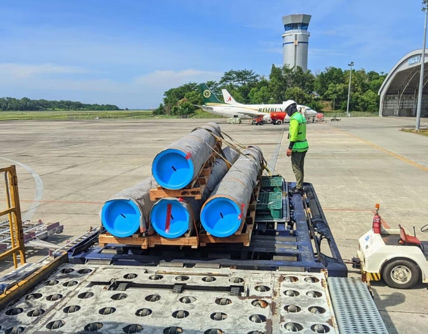 Pipa baja di atas palet di samping pesawat kargo charter
