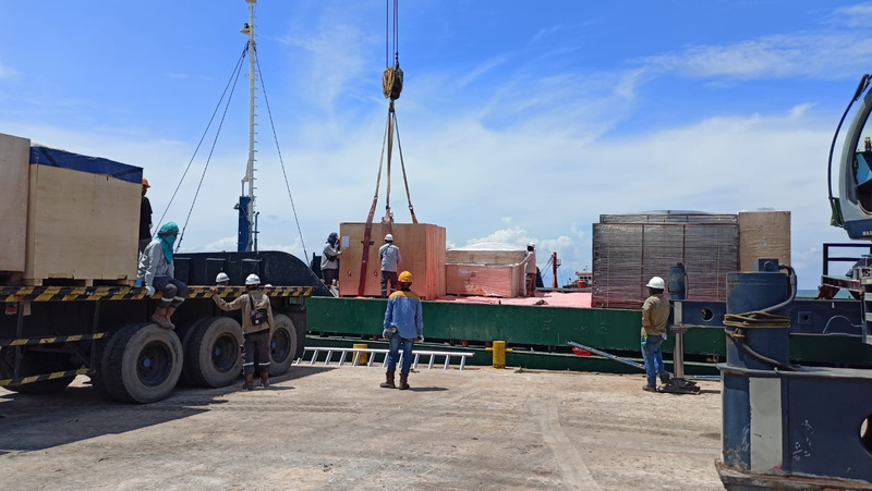 Kargo industri berkotak diangkat dari truk di samping kapal